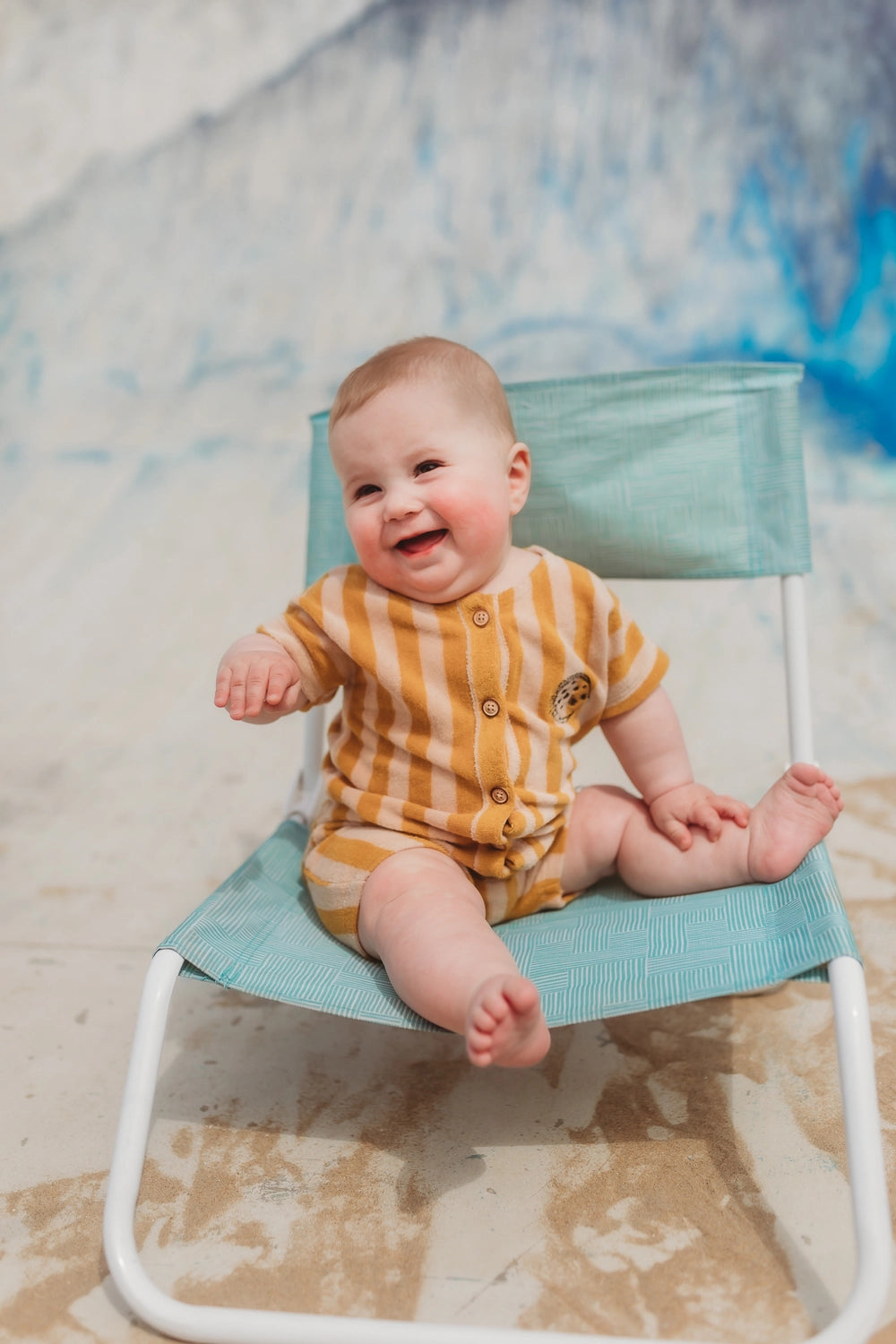 Baby Sproet & Sprout SS24 draagt badstof playsuit met gele en beige verticale strepen